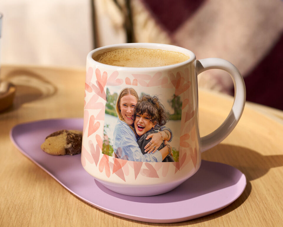 Eine personalisierte Tasse mit einem Foto von zwei lächelnden Personen, umgeben von einem herzlichen Muster.