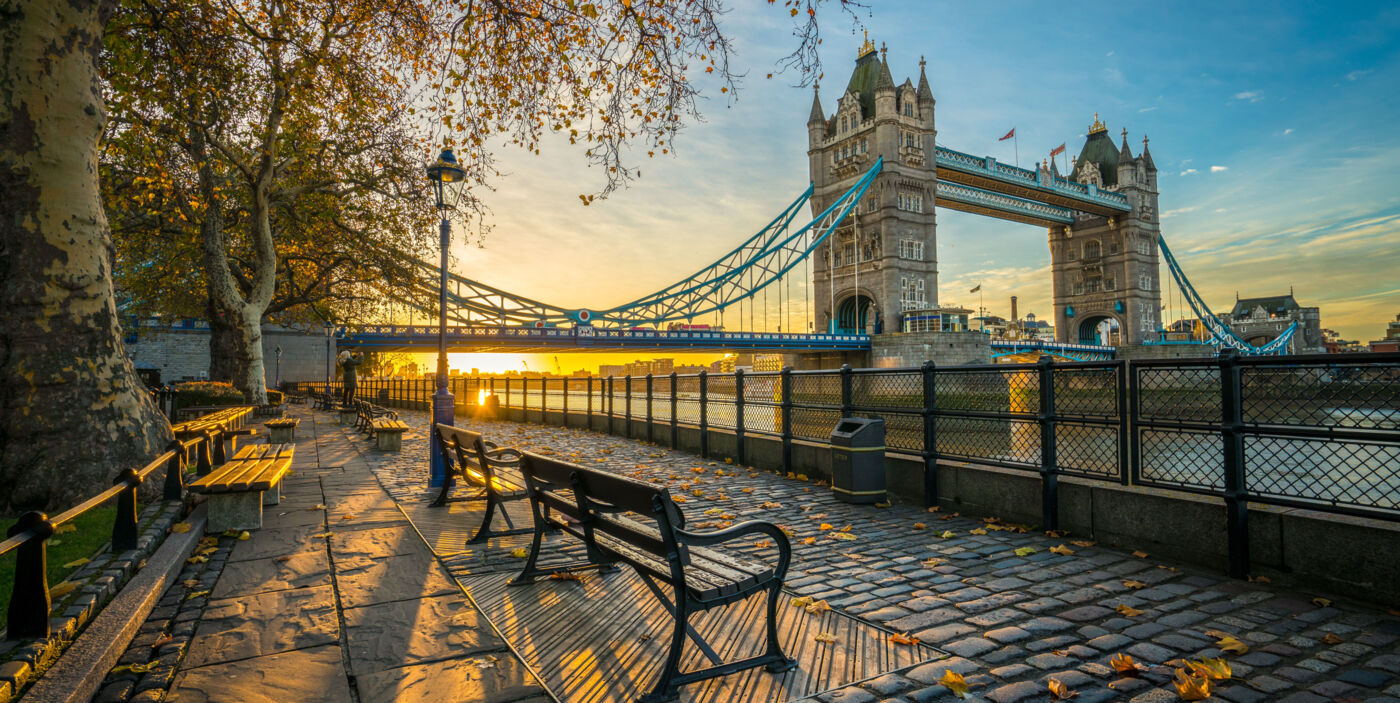 Einsame Uferpromenade der Themse bei Sonnenaufgang im Herbst. Im Hintergrund die Tower Bridge.